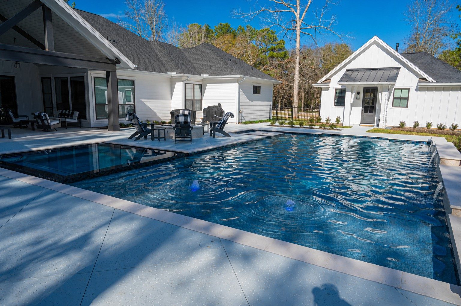 Poolside view of the modern farmhouse with Adirondack chairs on the white deck