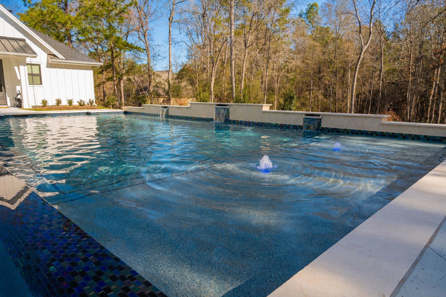 Raised wall with sheer-descent spillways and bubblers rippling the pool surface