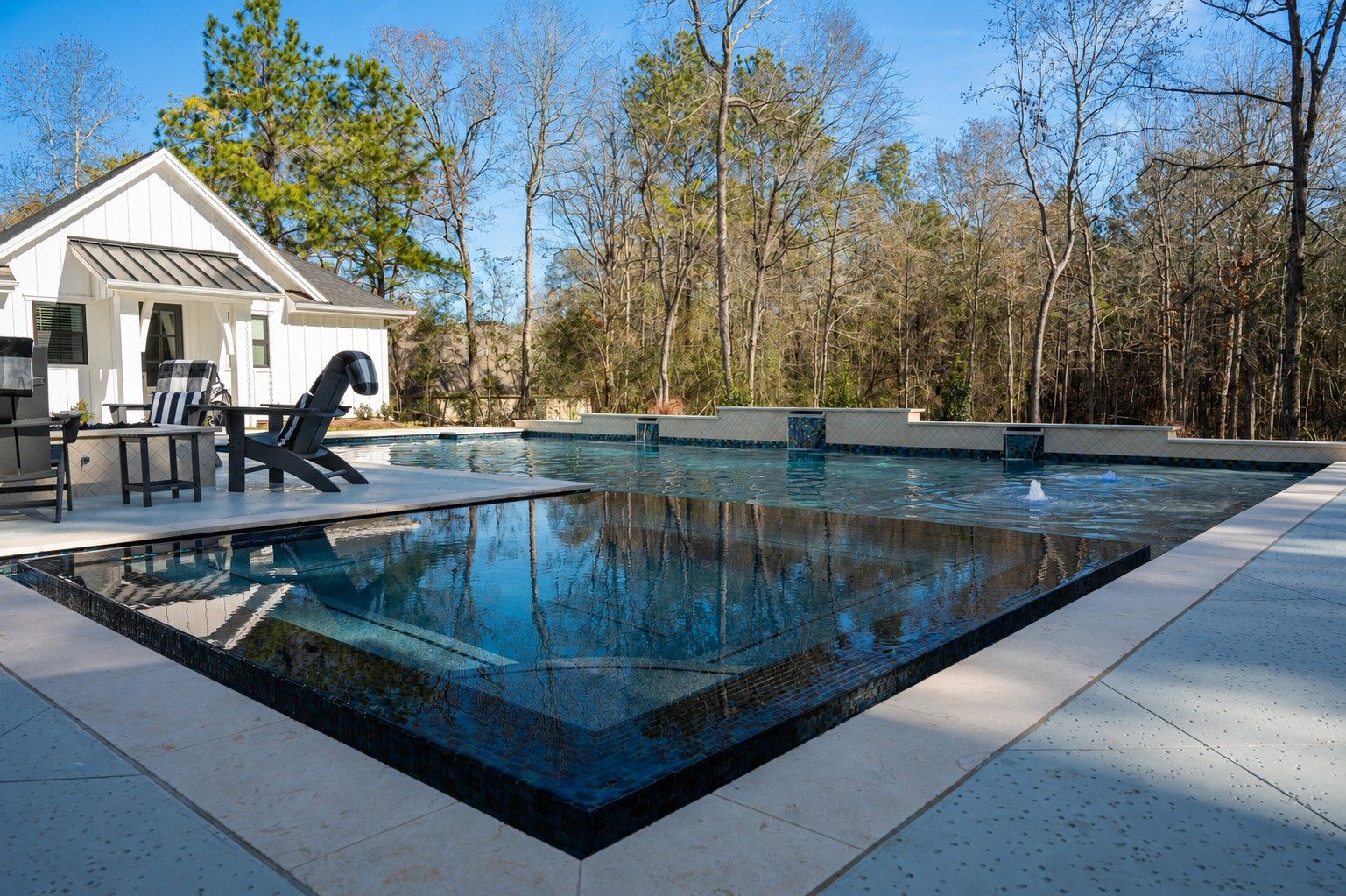 Long view down the geometric pool with clean coping lines and woodland backdrop