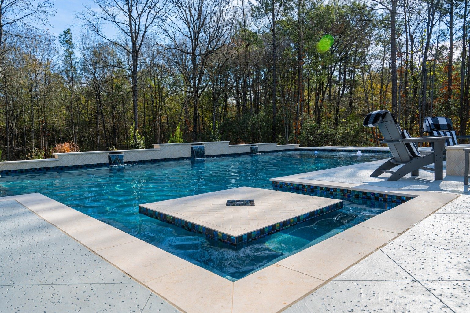 Swim-up table with glass-tile base in the foreground and the raised spillway wall beyond